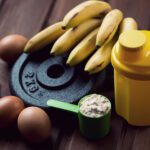 Shaker, measuring scoop with protein, eggs and bananas, close-up